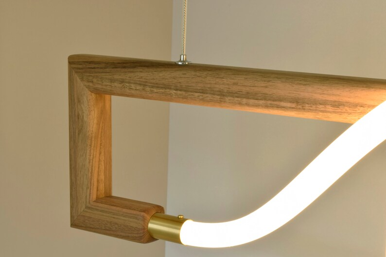 May include: A modern pendant light fitting with a wooden frame and a white LED light source. The light source is curved and appears to be floating within the frame.