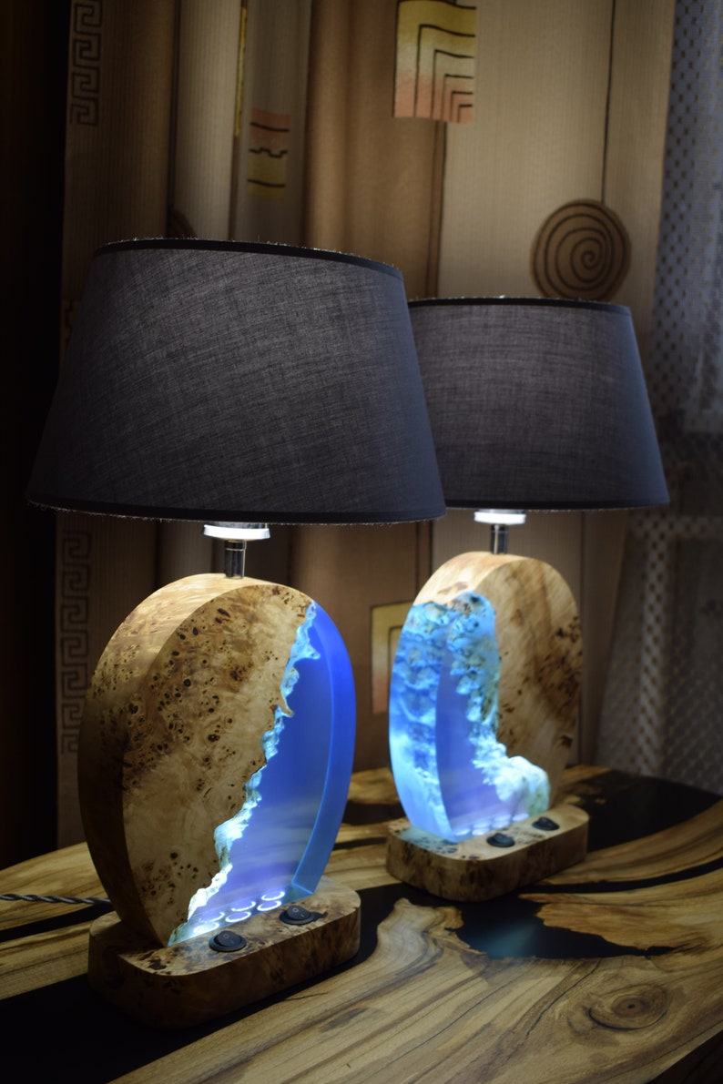 Puede incluir: Dos l&aacute;mparas de mesa de madera con incrustaciones de resina azul y pantallas de tela negra. Las l&aacute;mparas tienen un acabado de madera natural y est&aacute;n iluminadas con luz blanca c&aacute;lida.