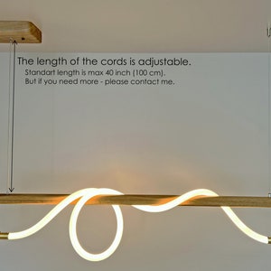 May include: A wooden light fitting with a white LED light that is shaped like a wave. The light is suspended from the ceiling by a cord that is adjustable up to 40 inches (100 cm).