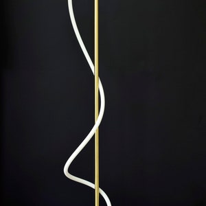 May include: A modern floor lamp with a white curved light fixture and a gold metal base. The base is made of wood and has a natural finish.
