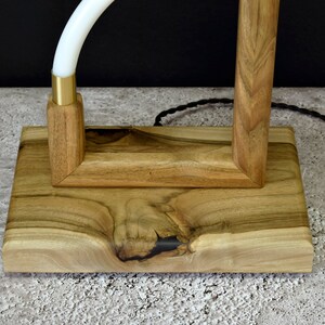 Pu&ograve; includere: Una base per lampada in legno con finitura in legno naturale. La base &egrave; rettangolare con un top quadrato e un fondo arrotondato. La base &egrave; realizzata in legno massello e presenta una venatura naturale.