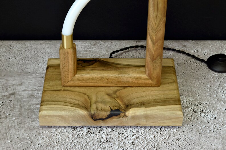 Pu&ograve; includere: Una base per lampada in legno con finitura in legno naturale. La base &egrave; rettangolare con un top quadrato e un fondo arrotondato. La base &egrave; realizzata in legno massello e presenta una venatura naturale.