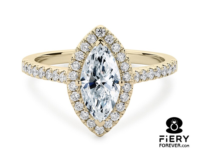 May include: A gold engagement ring with a marquise-shaped diamond center stone surrounded by a halo of smaller diamonds. The band is also set with smaller diamonds.