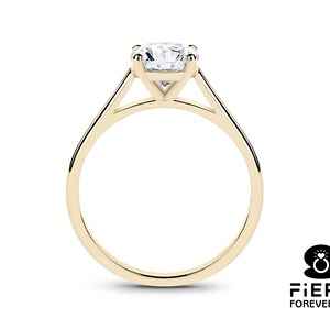 K&ouml;nnte beinhalten: Ein goldener Solit&auml;r-Verlobungsring mit einem runden Brillanten, der in einer schlichten, eleganten Fassung gefasst ist.