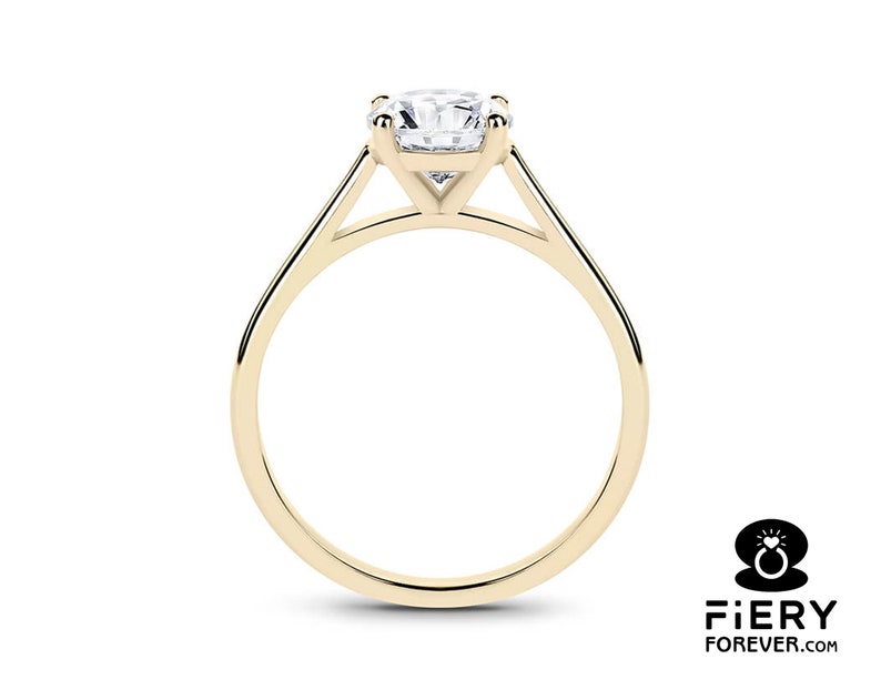 K&ouml;nnte beinhalten: Ein goldener Solit&auml;r-Verlobungsring mit einem runden Brillanten, der in einer schlichten, eleganten Fassung gefasst ist.