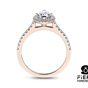 May include: A rose gold engagement ring with a pear-shaped center stone and a halo of smaller diamonds. The band is also set with smaller diamonds.