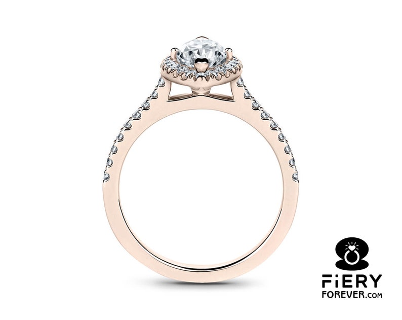 May include: A rose gold engagement ring with a pear-shaped center stone and a halo of smaller diamonds. The band is also set with smaller diamonds.