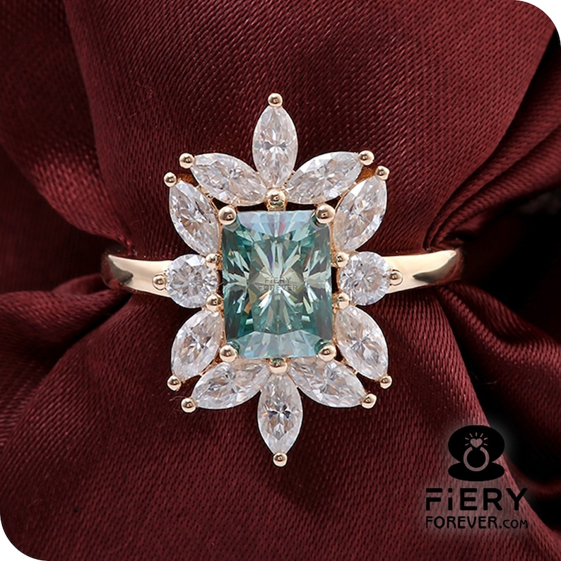 May include: A gold ring with a large, emerald-cut green gemstone surrounded by smaller, clear gemstones. The ring is set in a floral design.