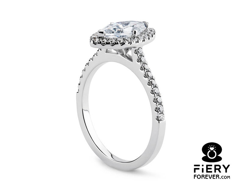 May include: A silver engagement ring with a marquise-shaped diamond center stone surrounded by a halo of smaller diamonds. The band is also set with smaller diamonds.