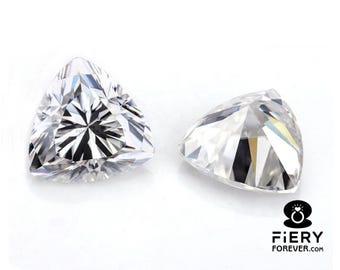 Puede incluir: Dos piedras preciosas triangulares transparentes con un diseño facetado. Las piedras preciosas están colocadas sobre un fondo blanco.
