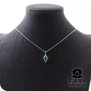 K&ouml;nnte beinhalten: Eine goldene Kettenkette mit einem gr&uuml;nen Edelstein-Anh&auml;nger in Diamantform.