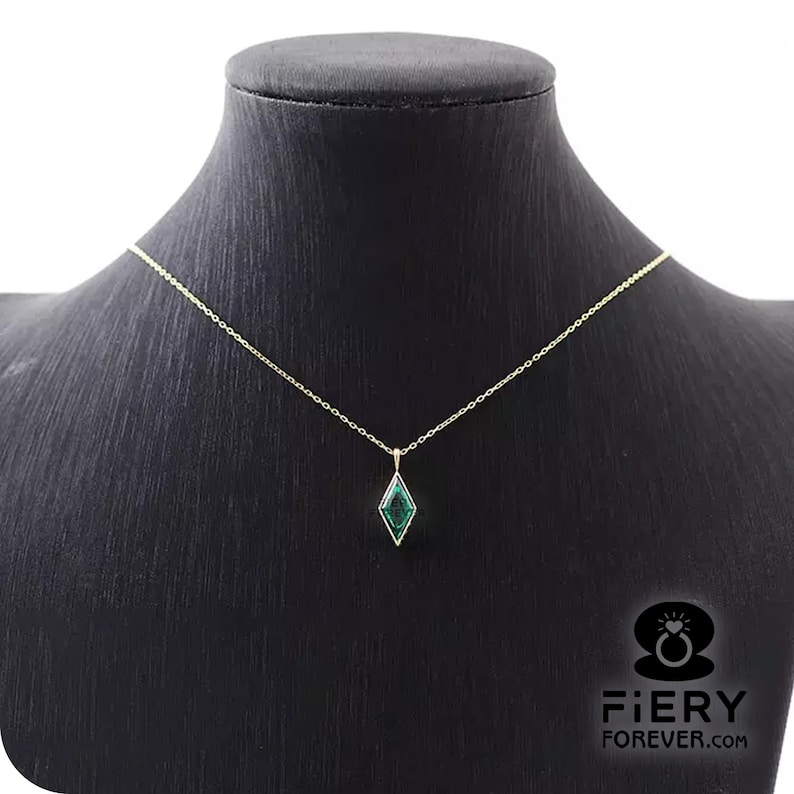 K&ouml;nnte beinhalten: Eine goldene Kettenkette mit einem gr&uuml;nen Edelstein-Anh&auml;nger in Diamantform.