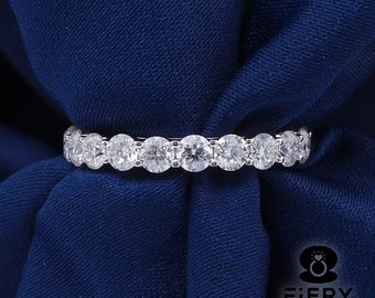 May include: A silver band ring with a row of round, clear gemstones set in a continuous line.