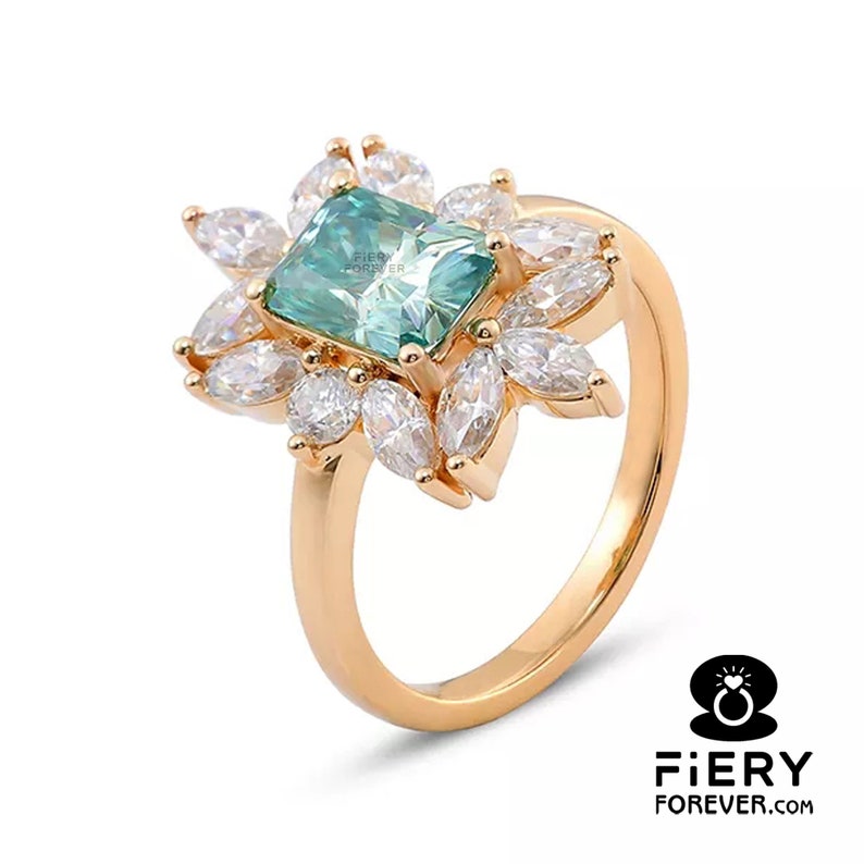 May include: A gold ring with a large, emerald-cut green gemstone surrounded by smaller, clear gemstones. The ring has a delicate, floral design.