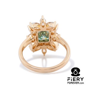 May include: A gold ring with a green gemstone surrounded by smaller clear gemstones in a floral design.
