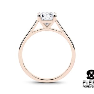 K&ouml;nnte beinhalten: Ein Verlobungsring aus Ros&eacute;gold mit einem Solit&auml;r-Diamanten in Krappenfassung. Der Ring hat ein schlichtes, elegantes Design mit einem dreieckigen Band.
