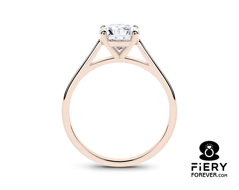K&ouml;nnte beinhalten: Ein Verlobungsring aus Ros&eacute;gold mit einem Solit&auml;r-Diamanten in Krappenfassung. Der Ring hat ein schlichtes, elegantes Design mit einem dreieckigen Band.