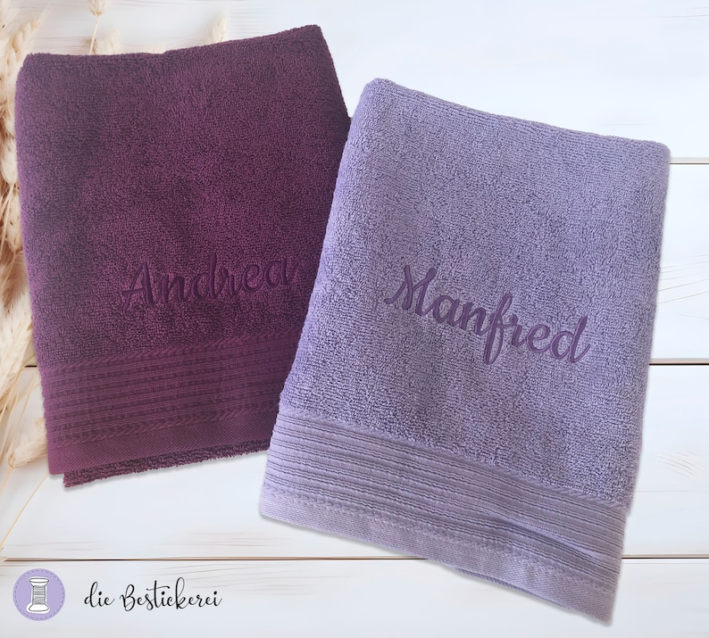 May include: Two personalized towels, one purple with the name "Andrea" embroidered on it and one light purple with the name "Manfred" embroidered on it.