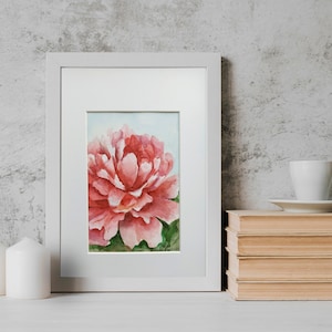 May include: A framed watercolor painting of a pink peony flower with green leaves. The painting is set against a white background.