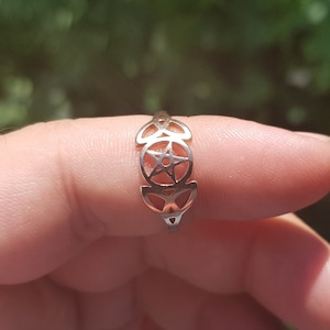 May include: A gold ring with a pentacle design, featuring a five-pointed star within a circle, surrounded by three crescent moons.