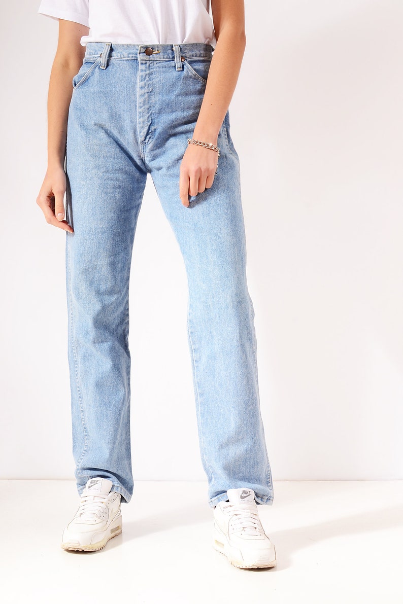 Op de afbeelding: Lichtblauwe denim jeans met een rechte pijp. De jeans heeft een hoge taille en een knoopsluiting. Het model draagt witte sneakers.