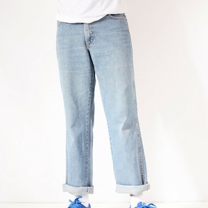 May include: A person wearing light blue denim jeans with a white t-shirt and blue trainers with a zebra print swoosh.
