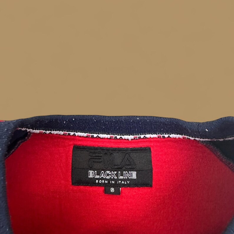May include: Red polo shirt with a navy blue collar and trim. The shirt features a black label with the text "BLACK LINE BORN IN ITALY" and the number 8.