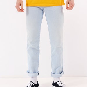 May include: A person wearing light blue jeans with the cuffs rolled up and black canvas sneakers with white laces.