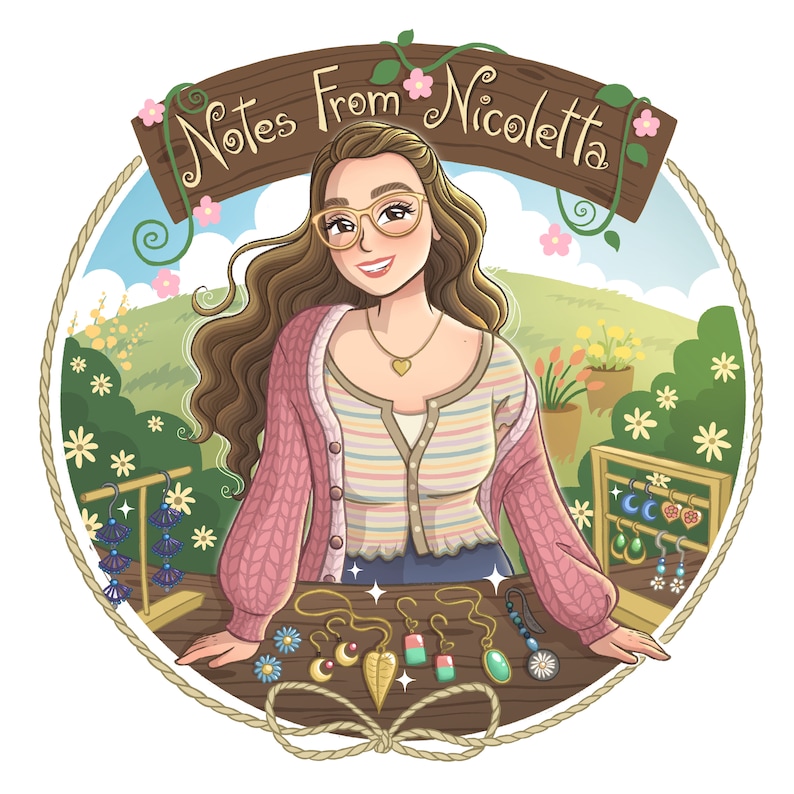 以下が含まれることがあります： 長い茶色の髪と眼鏡をかけた女性が、「Notes From Nicoletta」と書かれた看板のあるテーブルの後ろに立っています。テーブルは花で飾られており、さまざまなイヤリングが展示されています。イヤリングは金属、ガラス、木など、さまざまな素材で作られています。