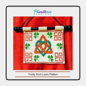 May include: A white beaded loom pattern with a red, orange, blue and green Trinity Knot design. The pattern is surrounded by green shamrocks and white squares. The pattern is hanging from a black dowel rod with a white background.