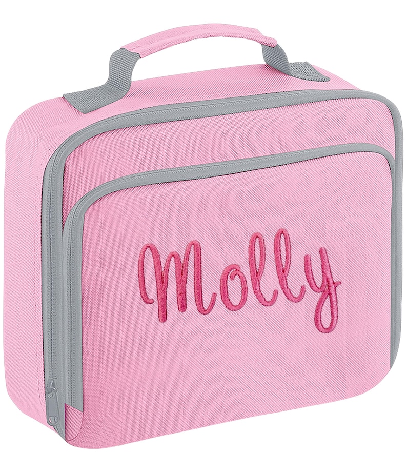 Puede incluir: Una bolsa de almuerzo rectangular de color rosa con ribetes grises y un asa superior. La parte frontal presenta el nombre Molly bordado en una letra cursiva de color rosa oscuro. La bolsa incluye un compartimento frontal y cierre con cremallera.