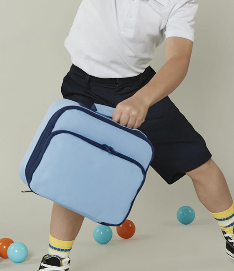 Puede incluir: Una bolsa de almuerzo rectangular de color azul claro con bordes en azul oscuro y una cremallera a juego. La bolsa cuenta con un asa superior para transportarla y un bolsillo frontal con cremallera, hecha de tela s&oacute;lida con dise&ntilde;o.