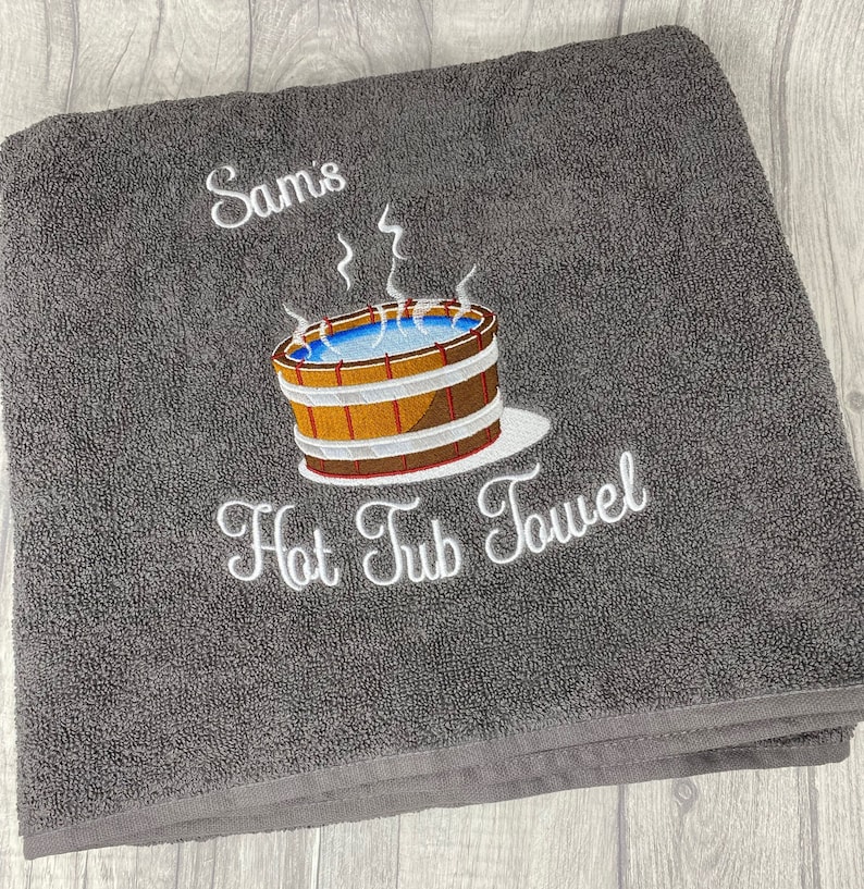 May include: Gray bath towel with white embroidery that says "Sam's Hot Tub Towel" and a cartoon image of a hot tub with steam rising from it.