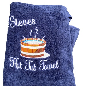 May include: A navy blue towel with white embroidery that says "Steve's Hot Tub Towel" and a cartoon image of a hot tub with steam coming off of it.
