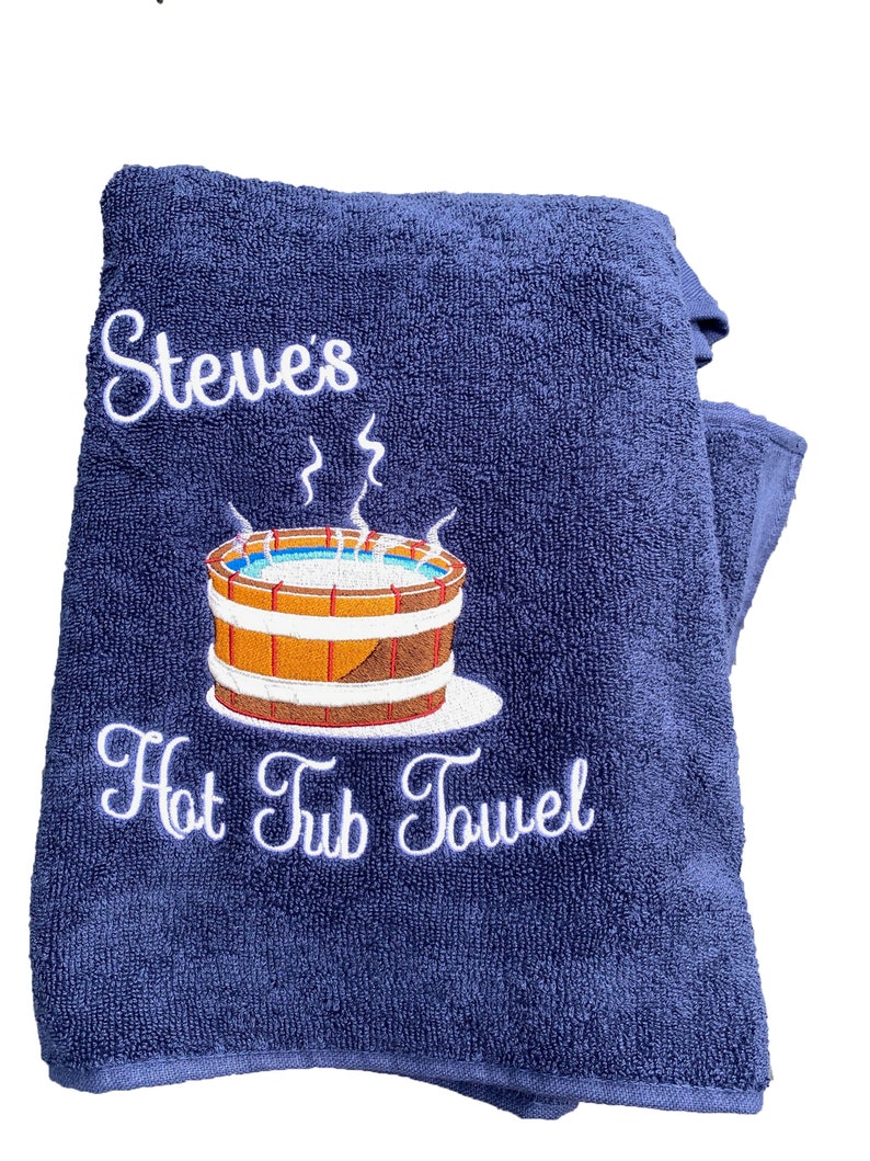 May include: A navy blue towel with white embroidery that says "Steve's Hot Tub Towel" and a cartoon image of a hot tub with steam coming off of it.