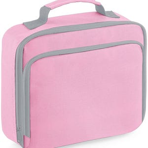 Puede incluir: Una bolsa de almuerzo rectangular de color rosa claro s&oacute;lido con ribetes grises y cierre de cremallera gris. La bolsa cuenta con un asa superior para llevarla y un bolsillo frontal con cremallera. El exterior es de tela texturizada.