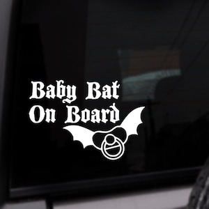Pu&ograve; includere:  Adesivo in vinile bianco con il testo "Baby Bat On Board" e un pipistrello stilizzato con un ciuccio in bocca.