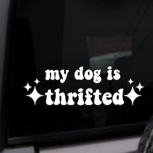 May include: White vinyl sticker with the text "my dog is thrifted" in a retro font. Two white stars are on either side of the text.