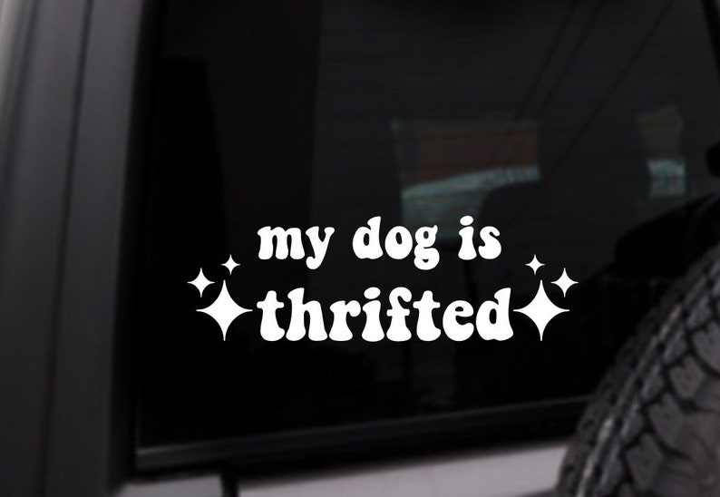 May include: White vinyl sticker with the text "my dog is thrifted" in a retro font. Two white stars are on either side of the text.
