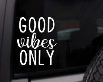 May include: White vinyl decal with the text "GOOD vibes ONLY" on a black background. The decal is attached to a car window.