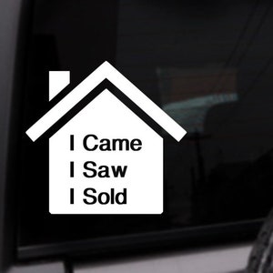 May include: White vinyl decal of a house with the text "I Came I Saw I Sold" inside. The decal is on a black car window.