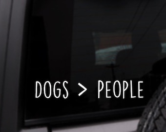 May include: A black car window with a white vinyl sticker that reads "DOGS > PEOPLE".