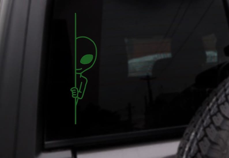 May include: A green alien peeking around a corner. The alien is drawn in a simple, cartoon style.