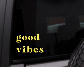 May include: A black car window with a yellow vinyl decal that reads "good vibes".