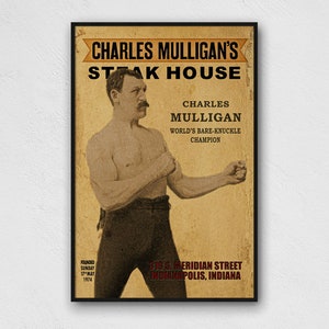 May include: A vintage poster advertising Charles Mulligan's Steak House. The poster features a black and white photo of Charles Mulligan, the "World's Bare-Knuckle Champion", in a fighting pose. The poster is in a black frame and has a brown background with red and yellow text. The text reads "Charles Mulligan's Steak House", "Charles Mulligan", "World's Bare-Knuckle Champion", "Founded Sunday 17th Mar 1974", and "238 S. Meridian Street Indianapolis, Indiana."