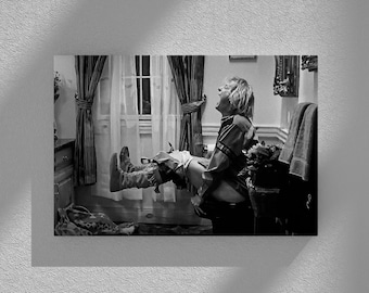 Può includere: Una foto in bianco e nero di una persona seduta sul water con le gambe alzate in aria. La persona indossa una camicia e pantaloni. La foto è scattata da un angolo basso.