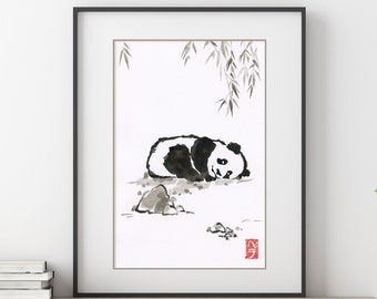 May include: Black and white ink painting of a panda bear sleeping under a willow tree. The painting is framed in a black frame and is hanging on a wall above a wooden shelf.