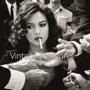 May include: A black and white photograph of a woman smoking a cigarette. She is surrounded by people, and one person is lighting her cigarette with a lighter. The photo has the text "Vintage Treasures" printed on it.