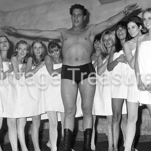 Könnte beinhalten: Eine Gruppe von Frauen in weißen Handtüchern steht in einer Reihe mit einem oben ohne Mann in der Mitte. Der Mann trägt eine schwarze Wrestling-Hose. Die Frauen lächeln alle und schauen in die Kamera.
