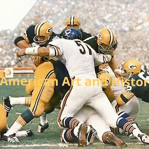 Puede incluir: Un grupo de jugadores de fútbol americano con uniformes verdes y amarillos están en una reunión durante un partido. Los jugadores llevan cascos y protecciones. Los jugadores están en un campo verde con una multitud de personas en el fondo.